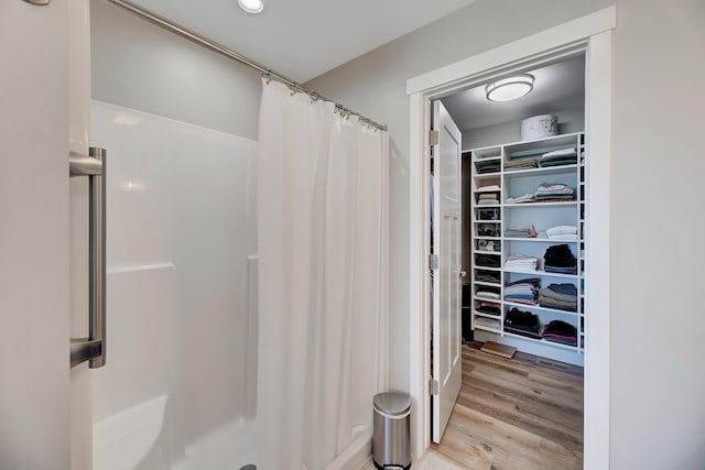bathroom featuring curtained shower, a spacious closet, and wood finished floors
