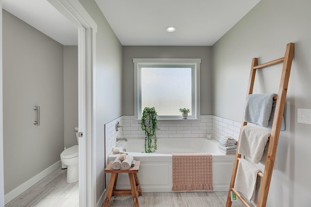 bathroom featuring toilet, a bath, and wood finished floors