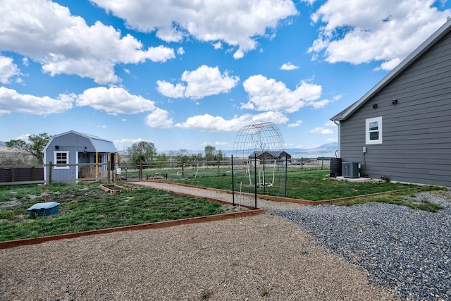 view of yard featuring a vegetable garden, central air condition unit, and an outbuilding