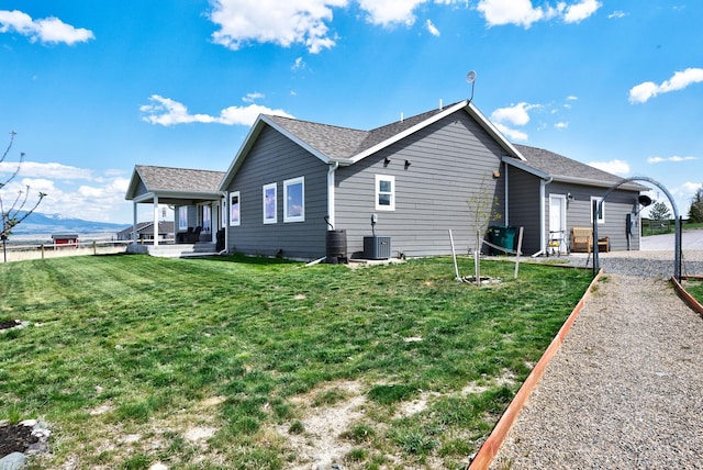 view of property exterior featuring a lawn, central AC unit, a shingled roof, and a patio area