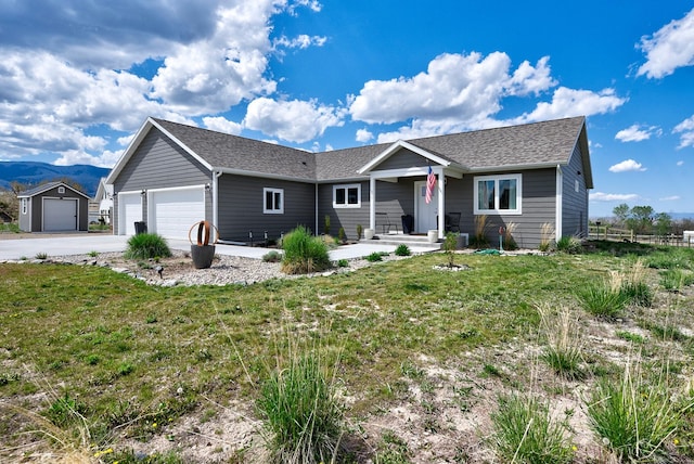 ranch-style home with a garage, concrete driveway, a front yard, and a mountain view