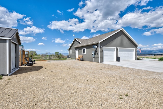 217 Spring St, Townsend, MT 59644 - view of side of property featuring concrete driveway, a shingled roof, and a garage