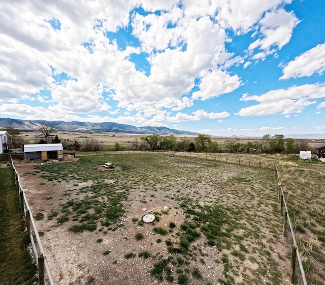 view of yard with a view of countryside, a mountain view, an outdoor structure, and fence