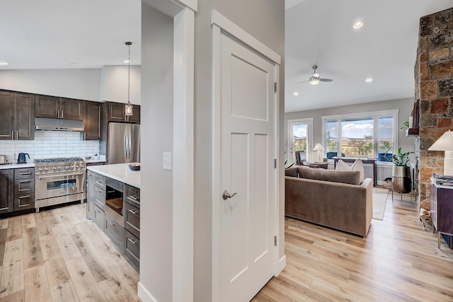 kitchen with stainless steel appliances, a ceiling fan, dark brown cabinets, backsplash, and light wood-style flooring