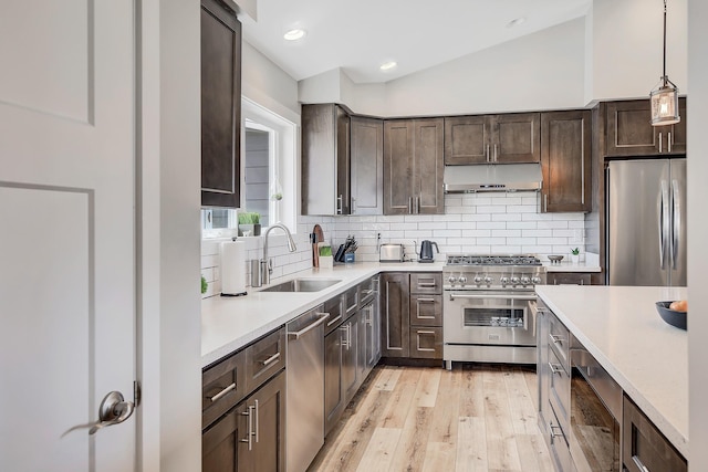 kitchen with stainless steel appliances, under cabinet range hood, a sink, dark brown cabinets, and light countertops