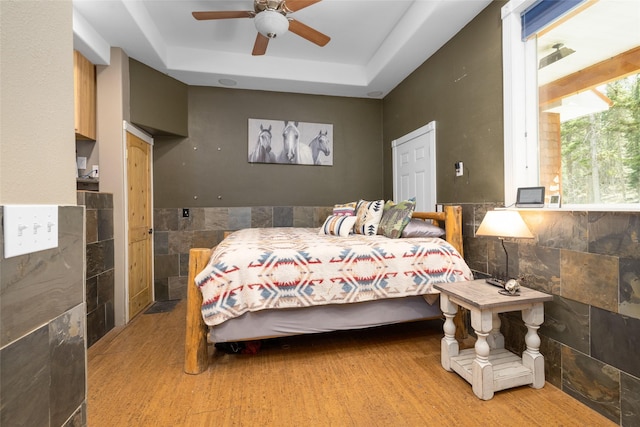 1492 Mcmannamy Draw, Kalispell, MT 59901 - bedroom with a tray ceiling, tile walls, light wood-type flooring, and a ceiling fan