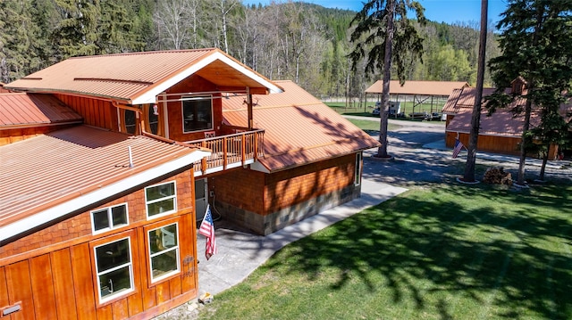 1492 Mcmannamy Draw, Kalispell, MT 59901 - view of property exterior featuring a forest view, a metal roof, a lawn, and a balcony
