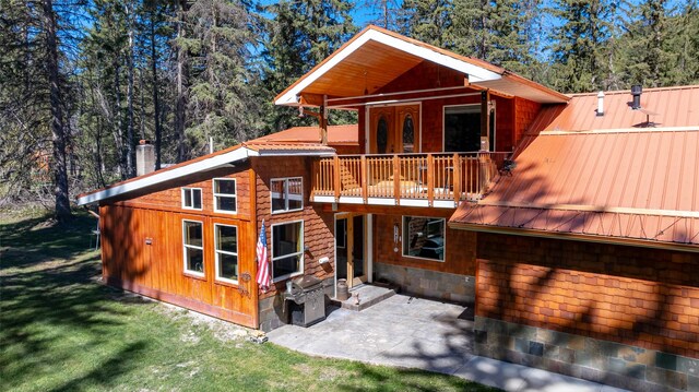 1492 Mcmannamy Draw, Kalispell, MT 59901 - rear view of house with a chimney, a patio area, a metal roof, a yard, and a balcony