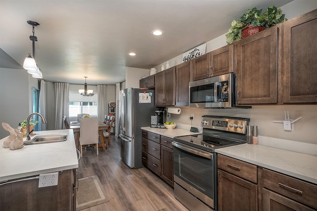 517 Raven Ln, Kalispell, MT 59901 - kitchen featuring stainless steel appliances, a chandelier, wood finished floors, dark brown cabinets, and decorative light fixtures
