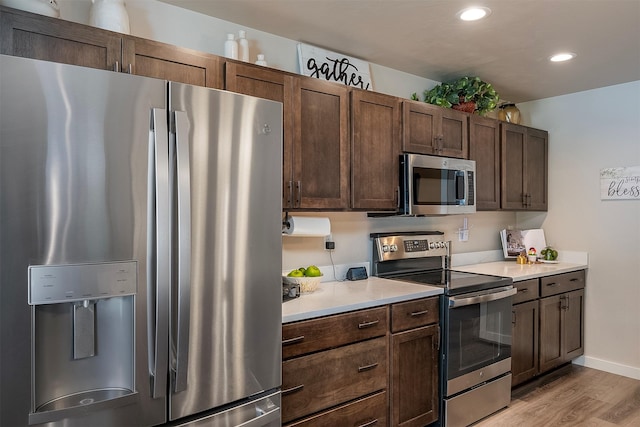 517 Raven Ln, Kalispell, MT 59901 - kitchen featuring appliances with stainless steel finishes, light wood finished floors, light countertops, dark brown cabinetry, and recessed lighting