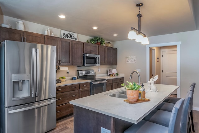 517 Raven Ln, Kalispell, MT 59901 - kitchen featuring appliances with stainless steel finishes, light wood-style flooring, dark brown cabinetry, a kitchen breakfast bar, and recessed lighting
