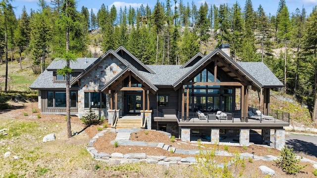 145 Elk Highlands Dr, Whitefish, MT 59937 - rear view of house with stone siding, a wooded view, a chimney, and roof with shingles