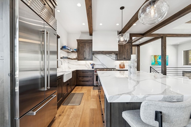 145 Elk Highlands Dr, Whitefish, MT 59937 - kitchen featuring high end appliances, beam ceiling, open shelves, light wood finished floors, and custom exhaust hood
