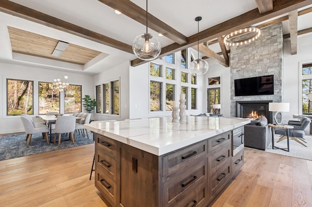 145 Elk Highlands Dr, Whitefish, MT 59937 - kitchen featuring open floor plan, a chandelier, a fireplace, light wood-type flooring, and beamed ceiling