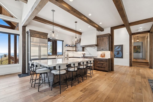 145 Elk Highlands Dr, Whitefish, MT 59937 - kitchen featuring beamed ceiling, a breakfast bar, built in fridge, light wood-style flooring, and a large island