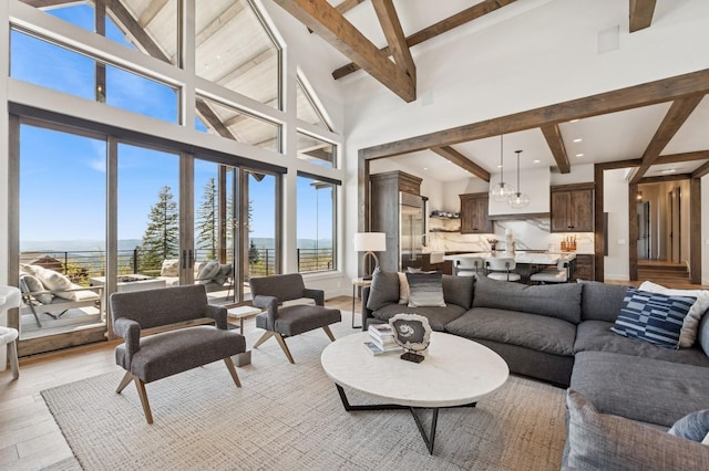 145 Elk Highlands Dr, Whitefish, MT 59937 - living room featuring beam ceiling, healthy amount of natural light, light wood-style floors, a high ceiling, and a water view