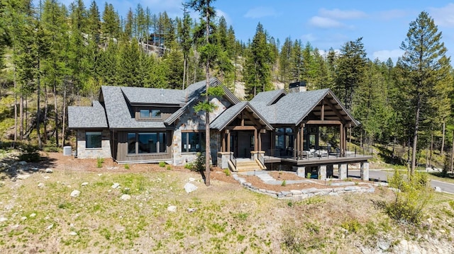 145 Elk Highlands Dr, Whitefish, MT 59937 - view of front facade featuring a wooded view, stone siding, and a chimney