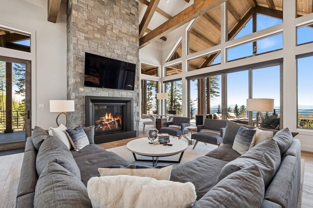 145 Elk Highlands Dr, Whitefish, MT 59937 - living area with a stone fireplace, beam ceiling, wood finished floors, high vaulted ceiling, and healthy amount of natural light