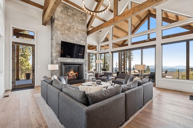 145 Elk Highlands Dr, Whitefish, MT 59937 - living room featuring beamed ceiling, high vaulted ceiling, a fireplace, light wood-style floors, and baseboards