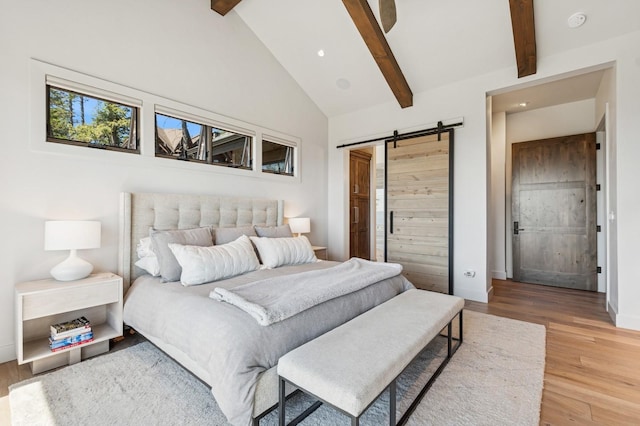 145 Elk Highlands Dr, Whitefish, MT 59937 - bedroom with a barn door, beam ceiling, light wood-type flooring, baseboards, and high vaulted ceiling