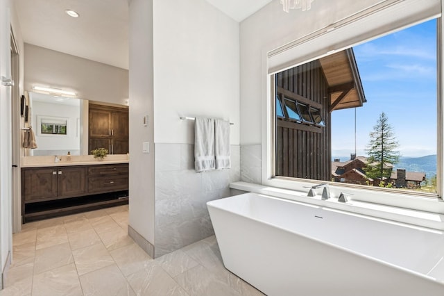 145 Elk Highlands Dr, Whitefish, MT 59937 - bathroom featuring tile walls, a freestanding tub, vanity, marble finish flooring, and wainscoting