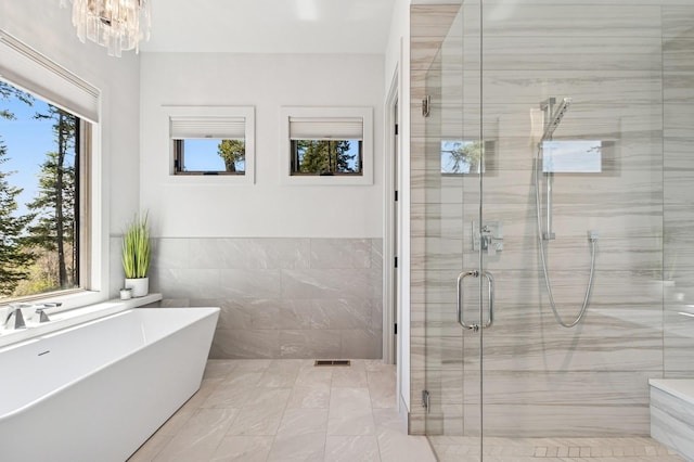 145 Elk Highlands Dr, Whitefish, MT 59937 - bathroom featuring plenty of natural light, a shower stall, a freestanding bath, tile walls, and a chandelier