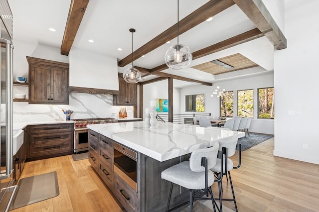 145 Elk Highlands Dr, Whitefish, MT 59937 - kitchen with stainless steel appliances, beamed ceiling, light wood finished floors, open floor plan, and light stone counters