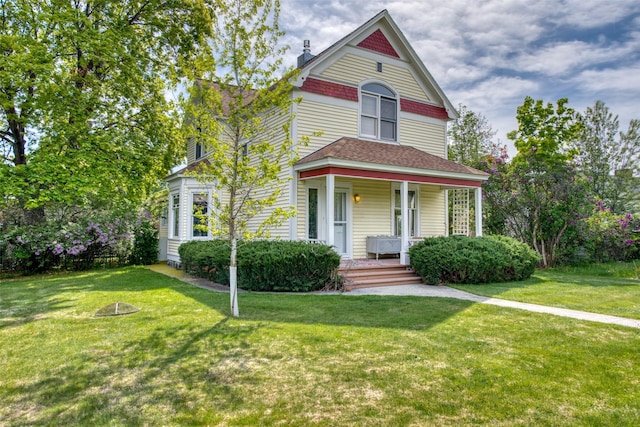 victorian house with a porch, a front lawn, roof with shingles, and a chimney