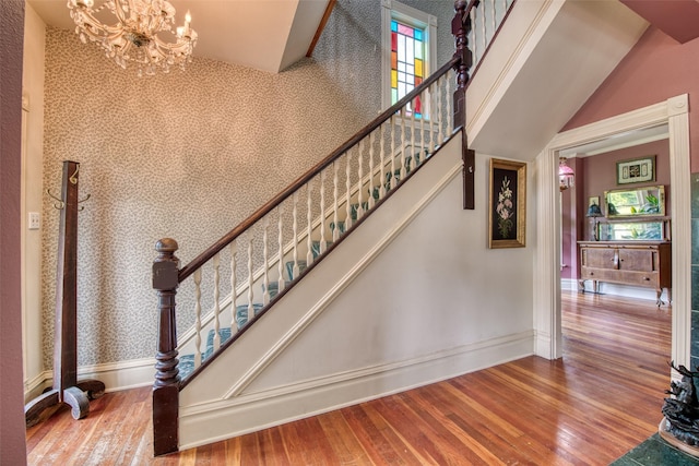staircase with wood finished floors, a chandelier, and baseboards