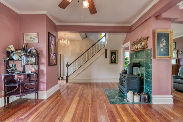 living room featuring a wood stove, hardwood / wood-style flooring, ceiling fan, stairway, and baseboards