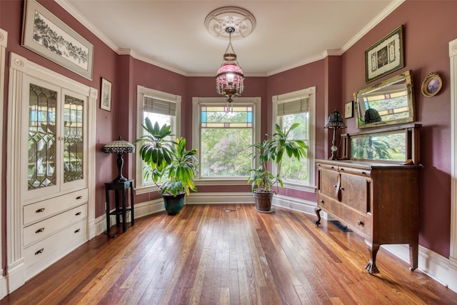 sitting room with hardwood / wood-style flooring, baseboards, ornamental molding, and a chandelier