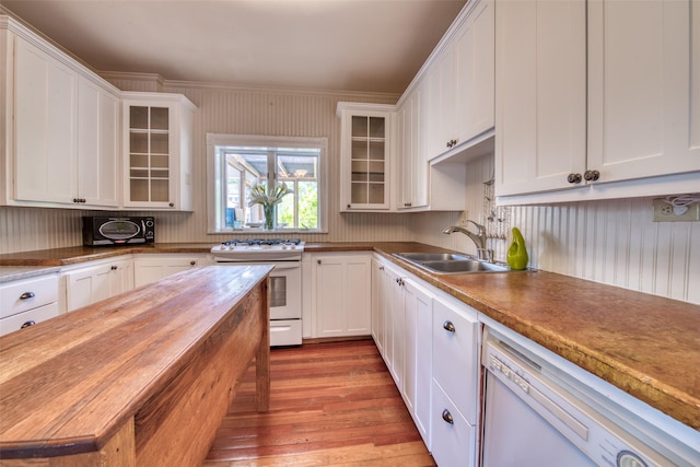 kitchen featuring white appliances, light wood finished floors, a sink, white cabinets, and glass insert cabinets