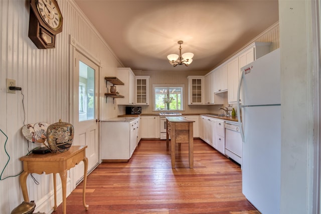 kitchen with white appliances, a chandelier, light wood-style flooring, glass insert cabinets, and white cabinets