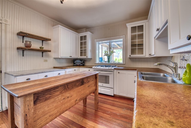 kitchen featuring gas range gas stove, a sink, ornamental molding, dark wood-style floors, and white cabinets