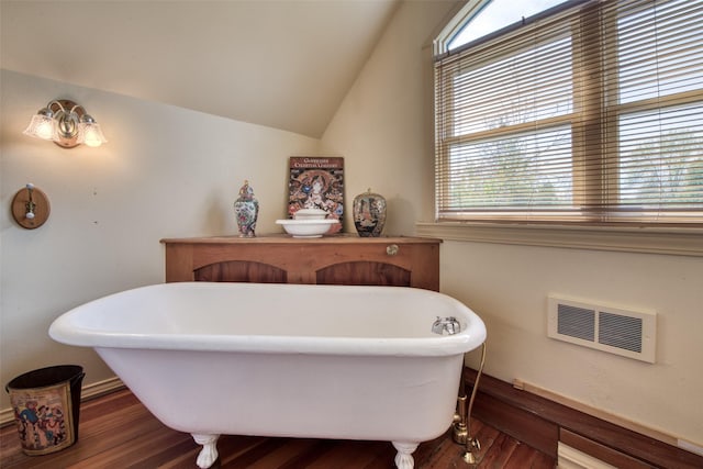 bathroom with plenty of natural light, a freestanding tub, wood finished floors, and lofted ceiling