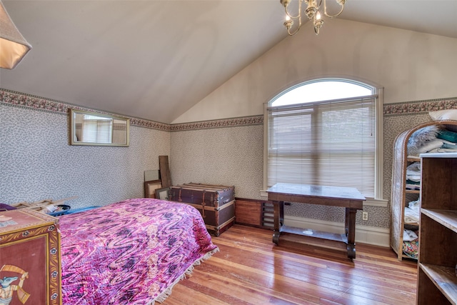 bedroom with wallpapered walls, lofted ceiling, hardwood / wood-style flooring, and a chandelier