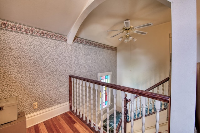 stairs featuring a ceiling fan, wood finished floors, wallpapered walls, beam ceiling, and baseboards