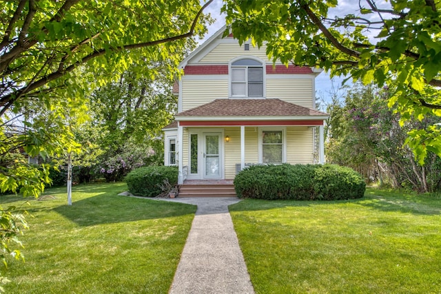 victorian house featuring a front lawn, a shingled roof, and a porch