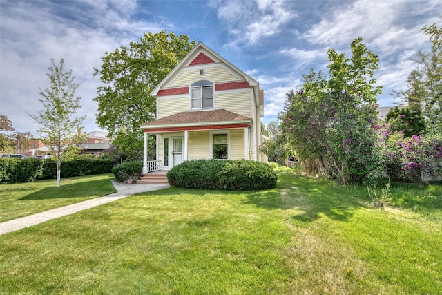 victorian-style house featuring covered porch, a front lawn, and a shingled roof