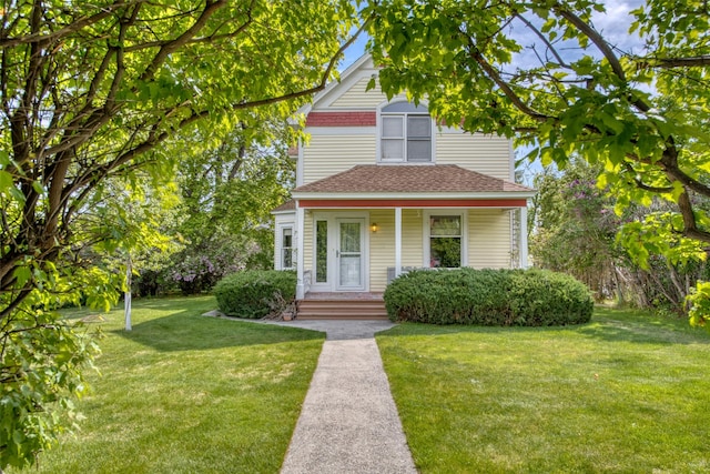 view of front of home with a front lawn, roof with shingles, and covered porch