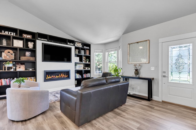 286 Ordway Dr, Florence, MT 59833 - living room featuring lofted ceiling, light wood finished floors, a glass covered fireplace, built in shelves, and baseboards