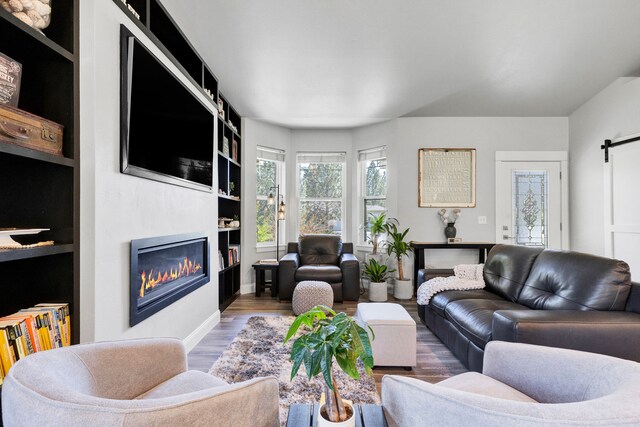 286 Ordway Dr, Florence, MT 59833 - living room with a glass covered fireplace, wood finished floors, a barn door, built in shelves, and baseboards
