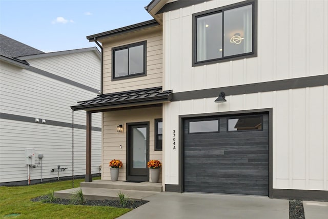 property entrance with a standing seam roof, metal roof, driveway, a garage, and board and batten siding