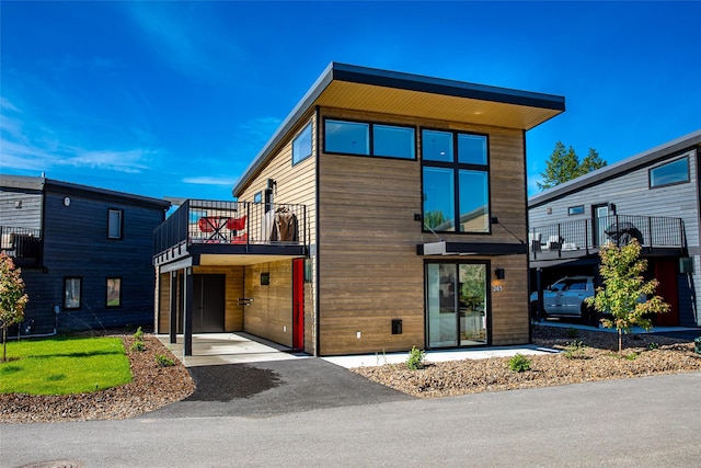 contemporary house featuring a balcony and asphalt driveway
