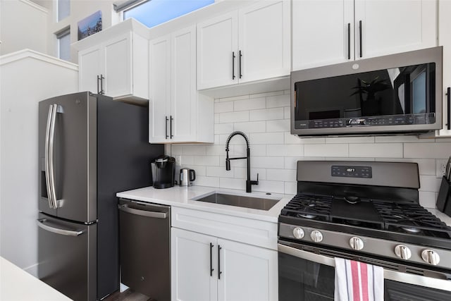 kitchen with appliances with stainless steel finishes, white cabinets, a sink, and decorative backsplash