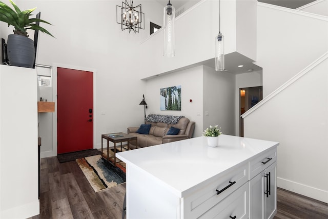 kitchen featuring dark wood-style floors, white cabinetry, a high ceiling, baseboards, and light countertops