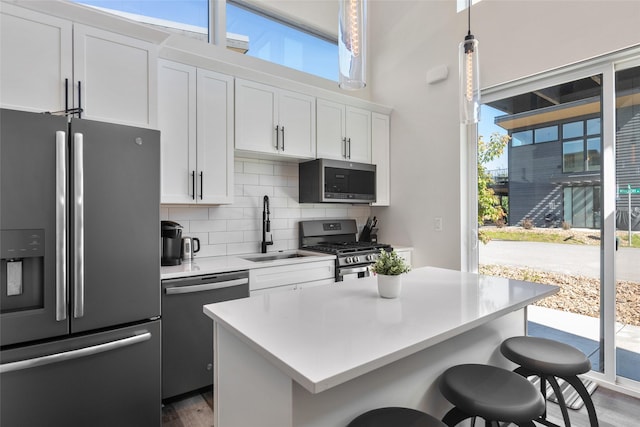 kitchen featuring appliances with stainless steel finishes, a sink, a kitchen breakfast bar, and plenty of natural light