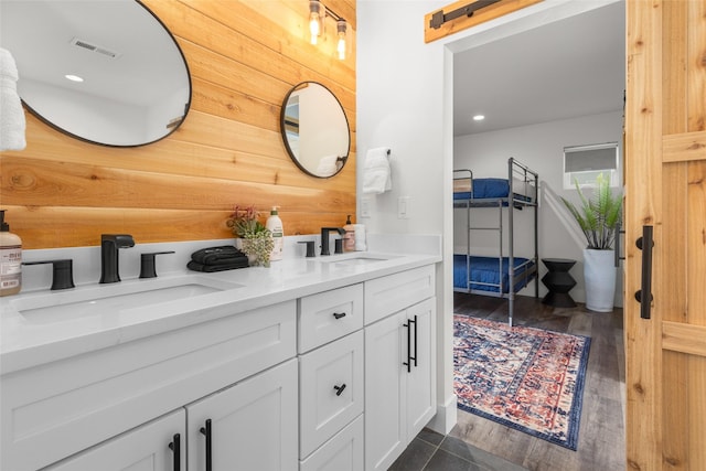 bathroom featuring wood finished floors, double vanity, and recessed lighting