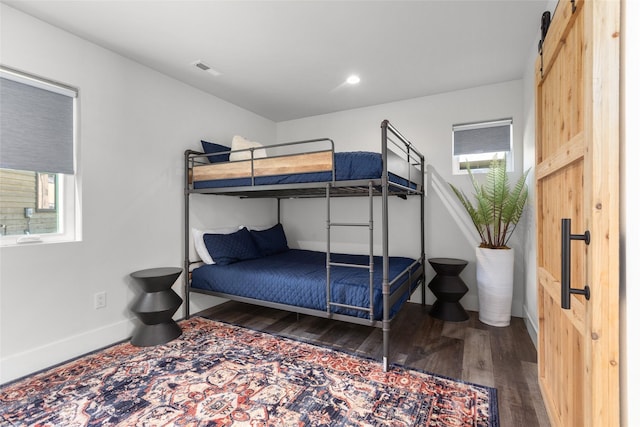 bedroom with wood finished floors, a barn door, and baseboards