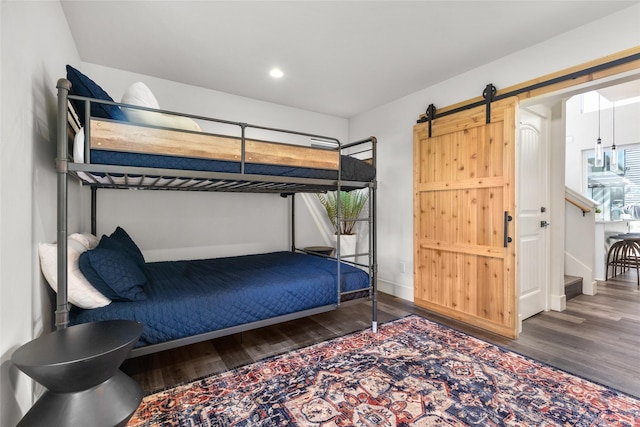 bedroom with wood finished floors, a barn door, and recessed lighting